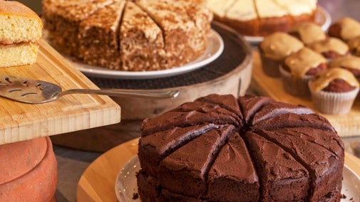 A table full of different types of sponge cake sliced and presented on cake stands ready to eat